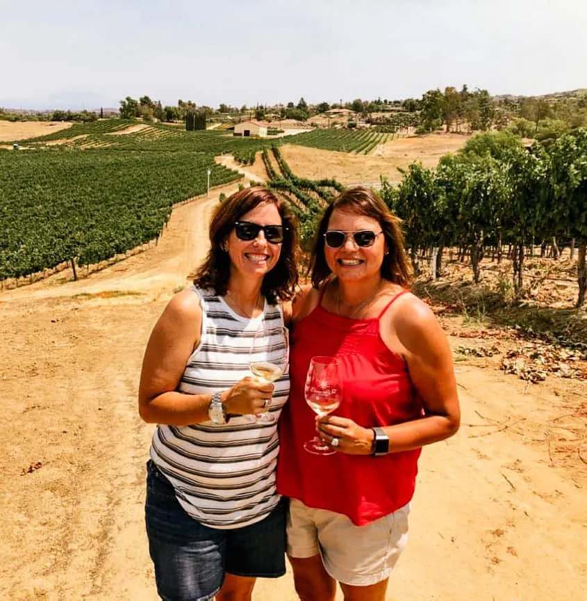 Nancy & Laura Hughes posing for a photo with white wine at Danza del Sol Winery vineyard
