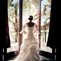 Bride stepping off onto a terrace through glass doors