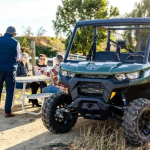 Winery tour host entertaining tour customers while tourists laugh and smile while enjoying wine on a wooden picnic table
