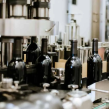 A wine bottling machine in action, with bottles moving along the conveyor and being processed in the production line.