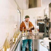 Winemaker Justin Knight checking bottles of wine on a conveyor belt during the bottling process.