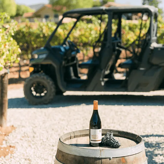 Danza Del Sol Wine Bottle on display in front of an ATV parked next to a vineyard